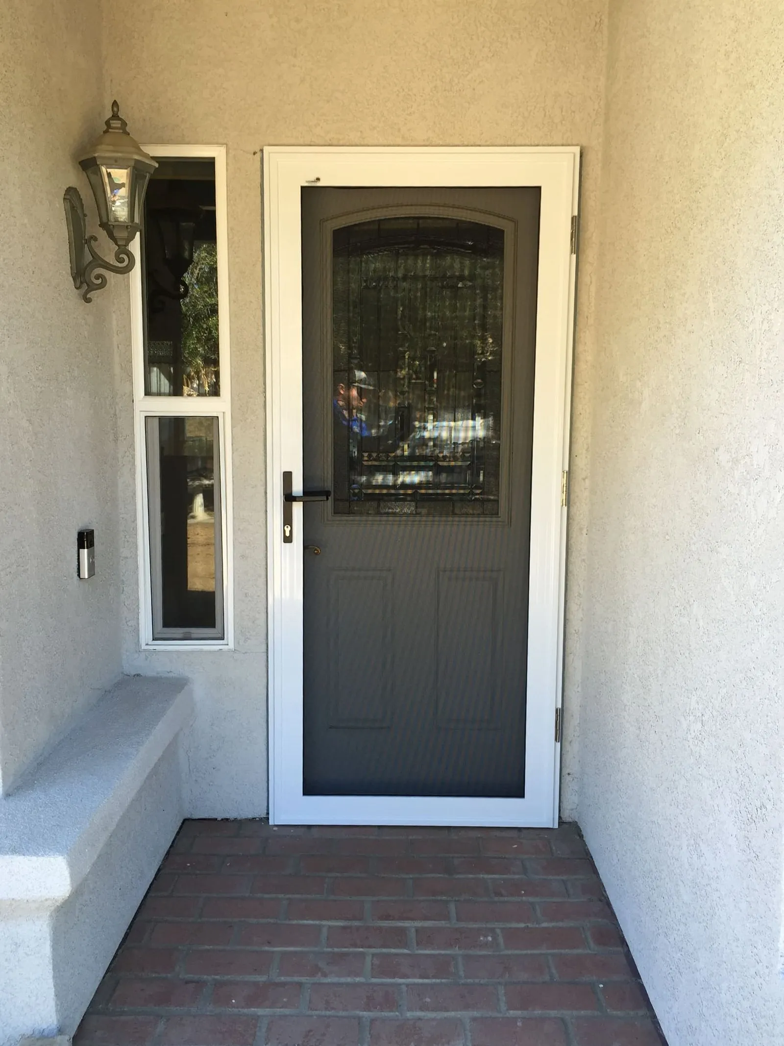 The same brick-step entry with a white hinged security screen door installed