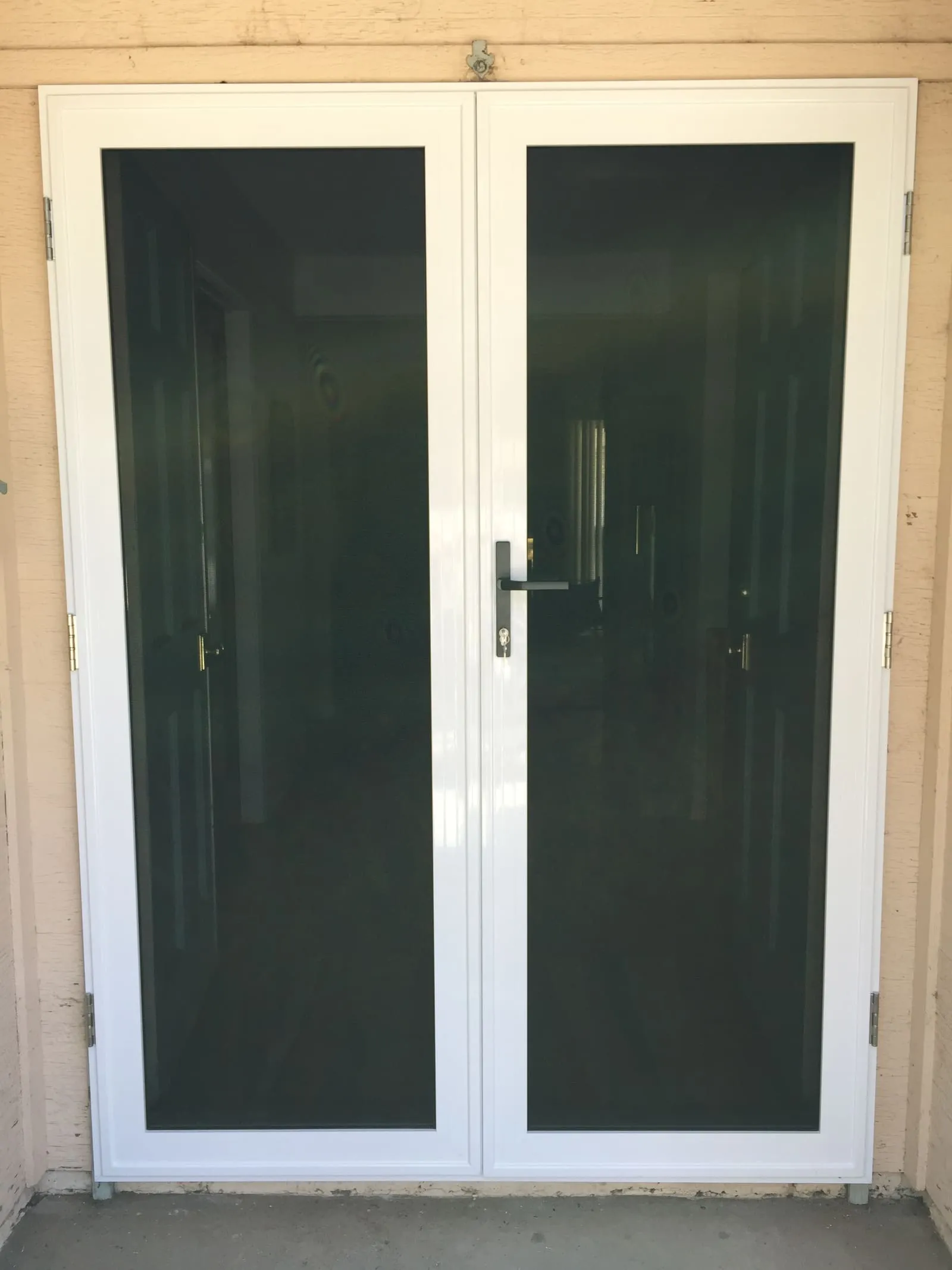 The same double doorway fitted with a new white French-pair security screen, both leaves full mesh