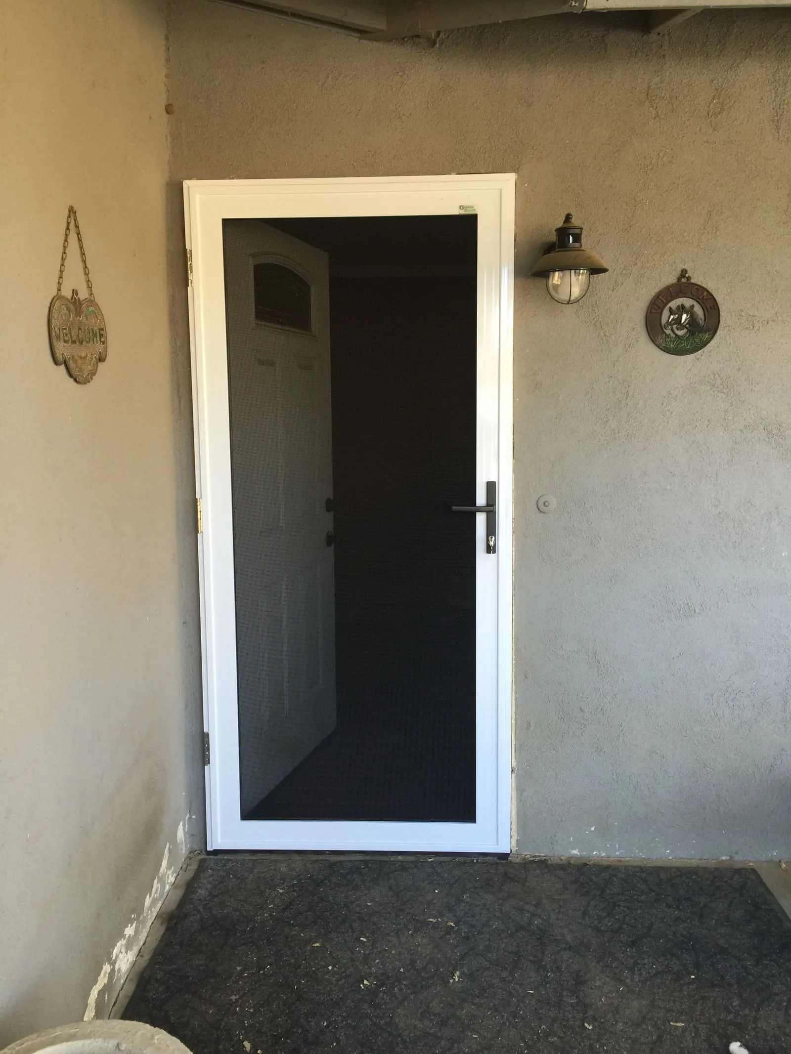 The same gray stucco entry with a white full-view security screen door installed