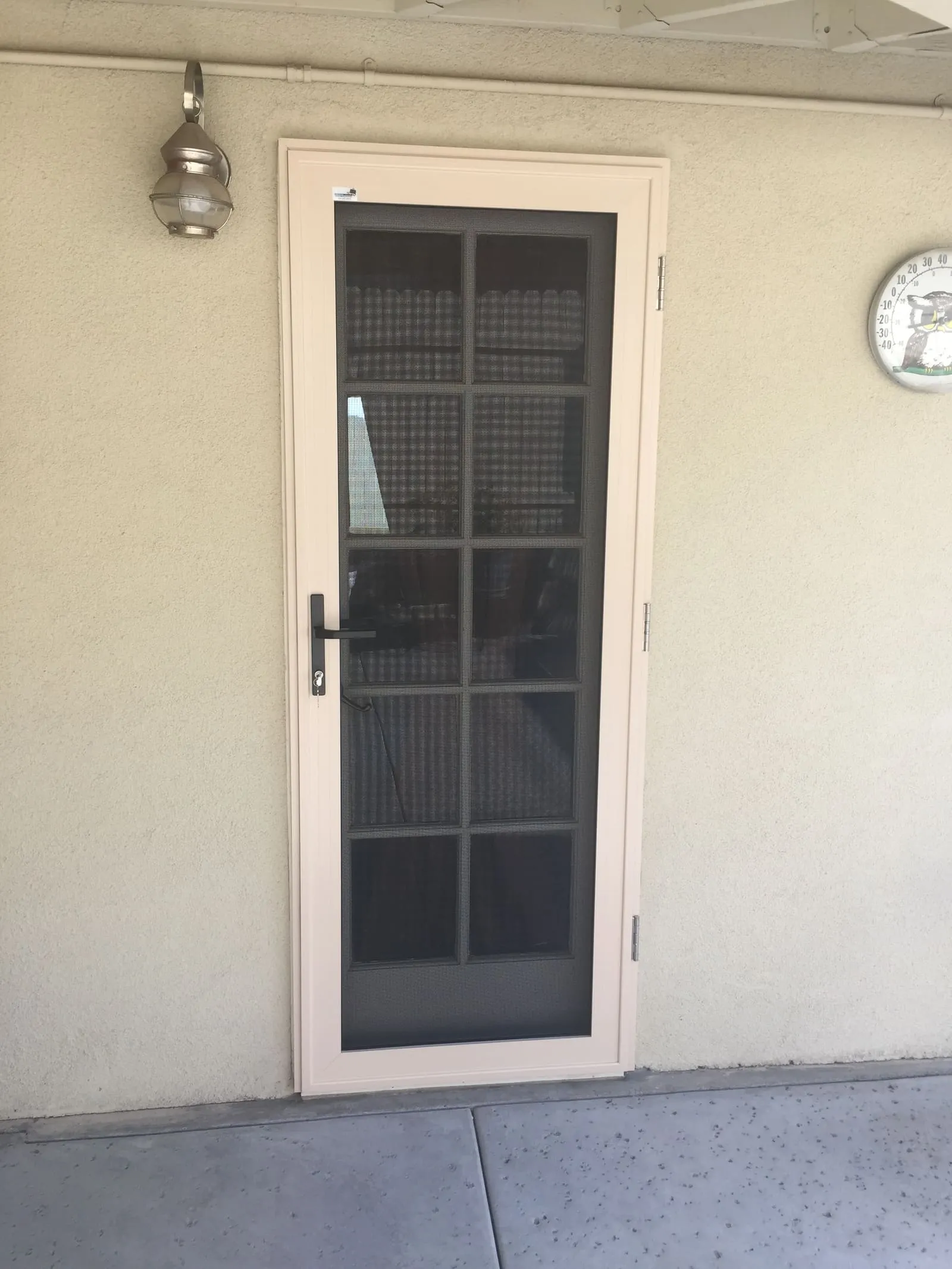 Almond hinged security screen door with a ten-lite glass door showing clearly through the mesh behind it