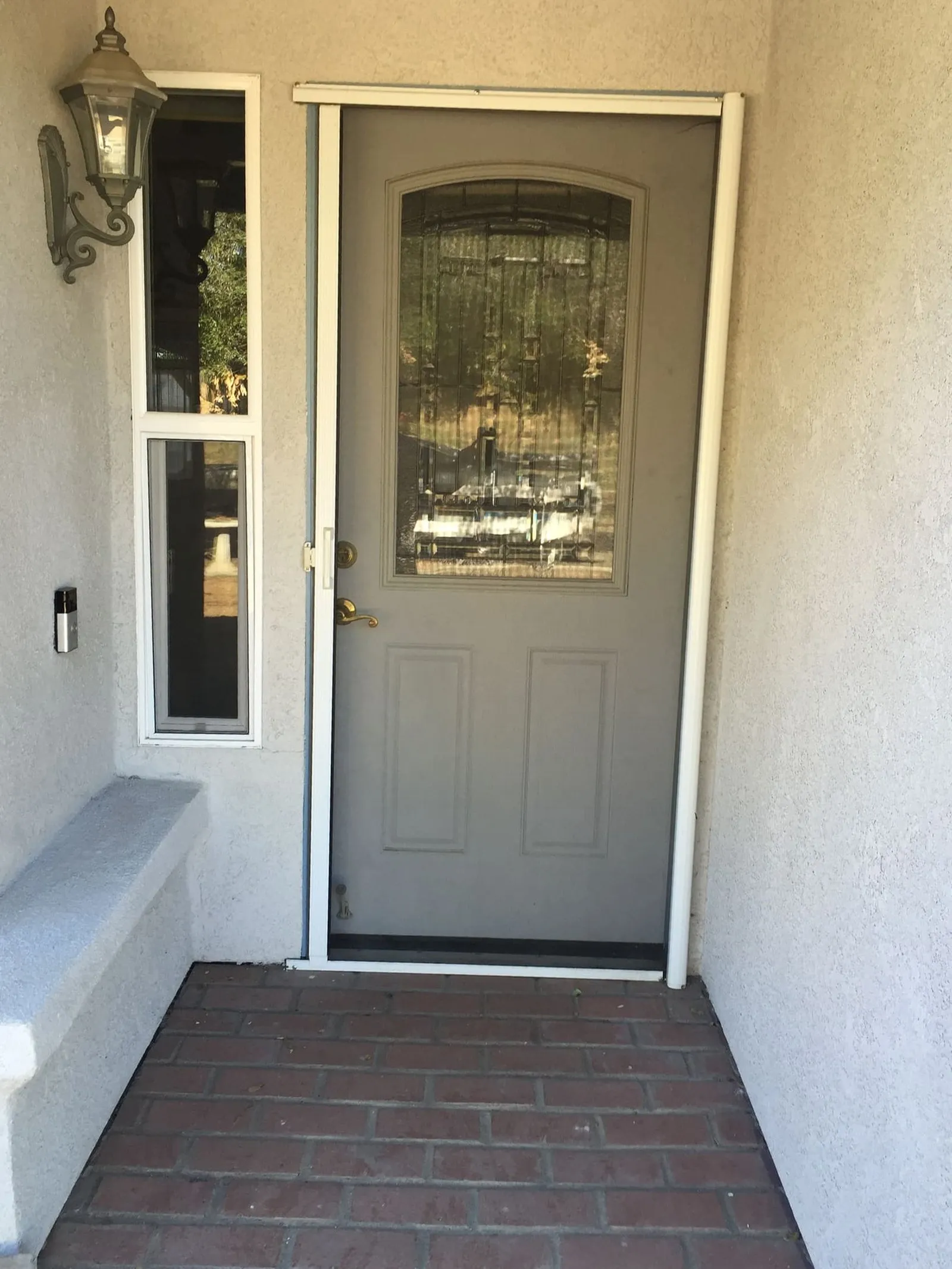 A front entry on a brick step with a glass-lite door and no screen layer