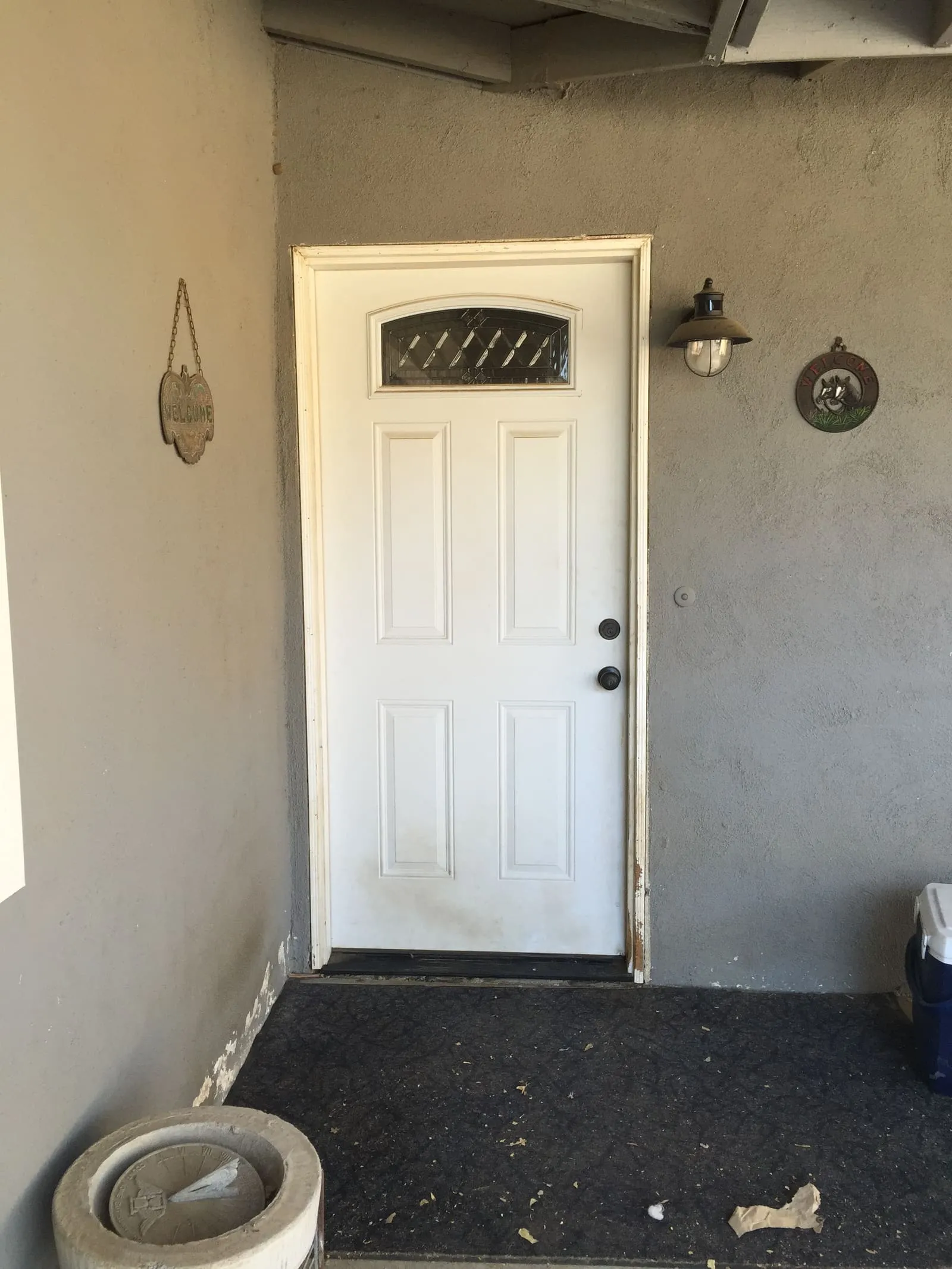 A plain solid entry door on gray stucco with no screen door
