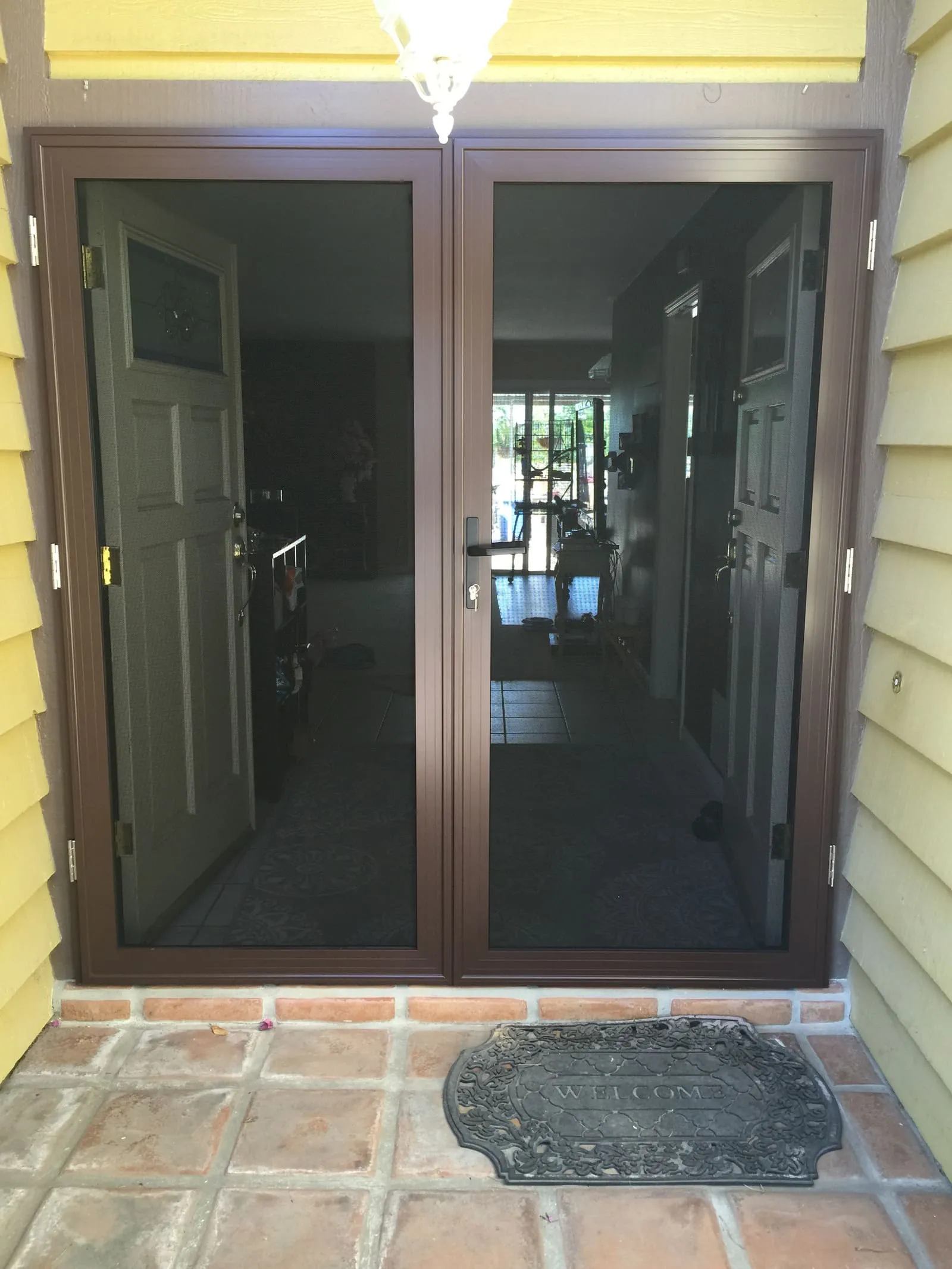 Dark bronze French-pair security screens on a Spanish-tile porch
