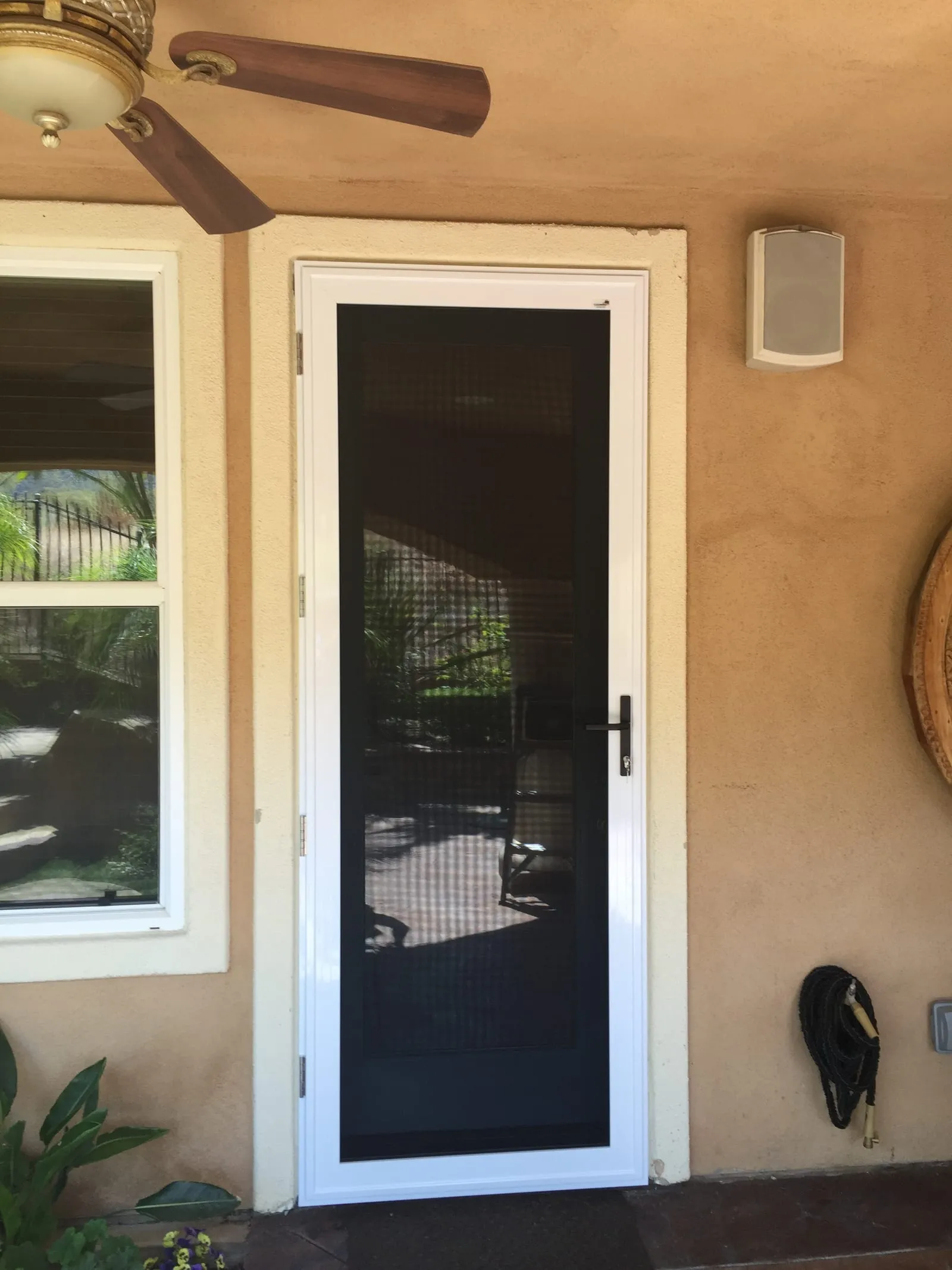 White hinged security screen door on a peach stucco porch