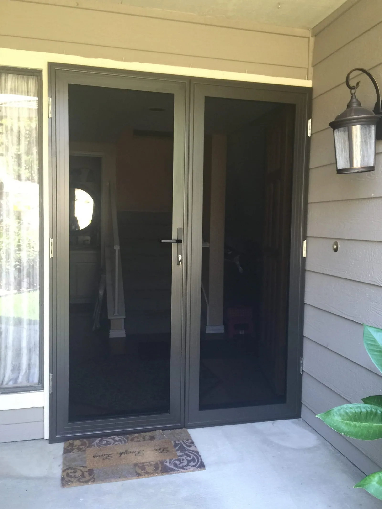 Bronze French-pair security screen doors installed on a covered porch