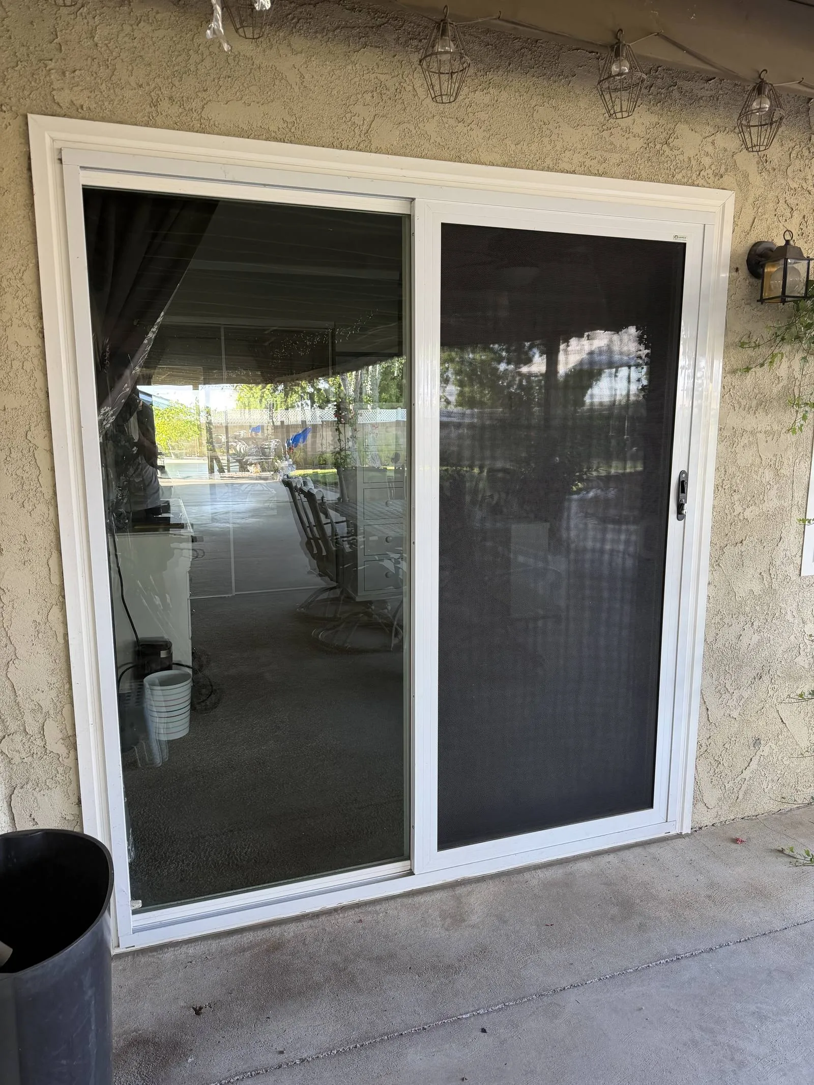 White-framed sliding security screen door on a covered patio slider, dark 316 mesh beside the open glass panel